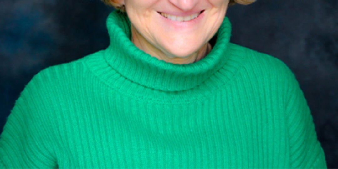 Headshot of Kalina Hristova. She is wearing a green turtleneck sweater and black square rimmed glasses. She has light skin tone, cheekbone length blonde hair with bangs, and dark color eyes.