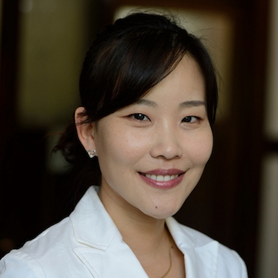 Headshot of Soojung Claire Hur. She has brown eyes and her dark hair pulled low behind her head. She is wearing a white lab coat.