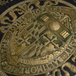 Closeup photograph of Johns Hopkins seal. It is on the floor in gold and black.