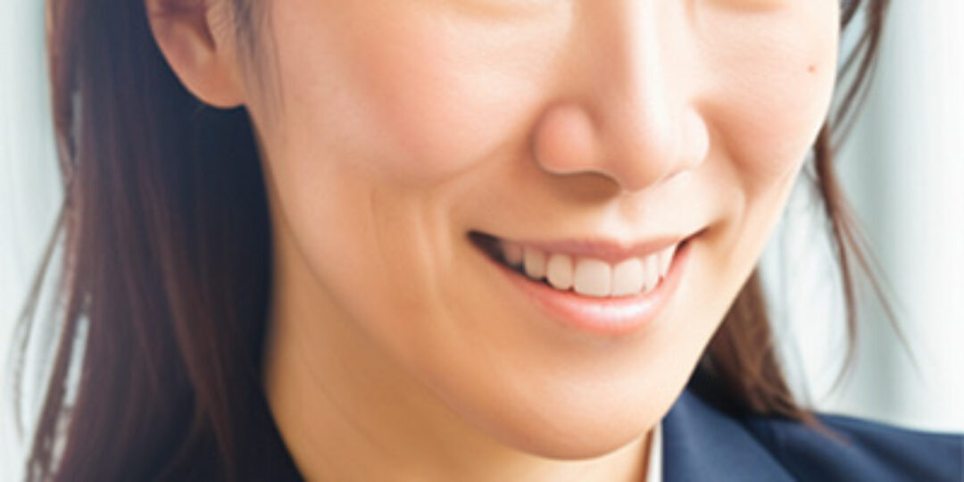 Headshot of Yun Chen. She brown, almond-shaped eyes and long brown hair with bangs. She is wearing a black collared blazer over a white collared shirt.